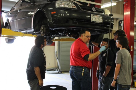 Mr. Carlos Martinez shows his students how to change oil.