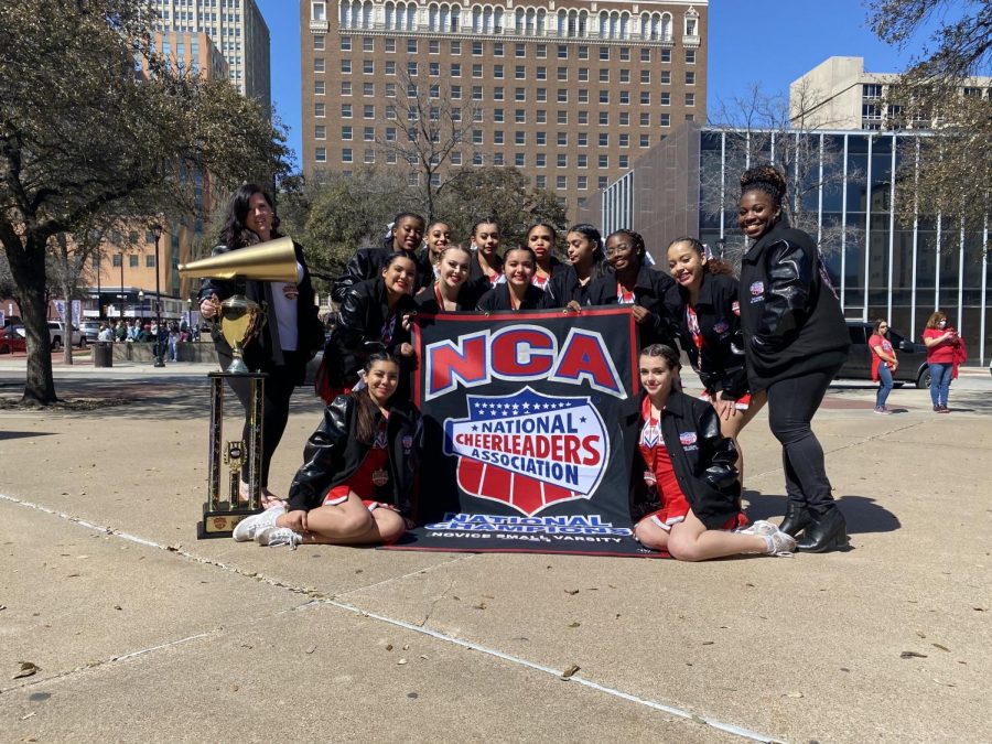 The cheerleaders pose with their national championship trophy and banner after their competition. This is the first time in 21 years the cheer team has brought back a national title to the campus.