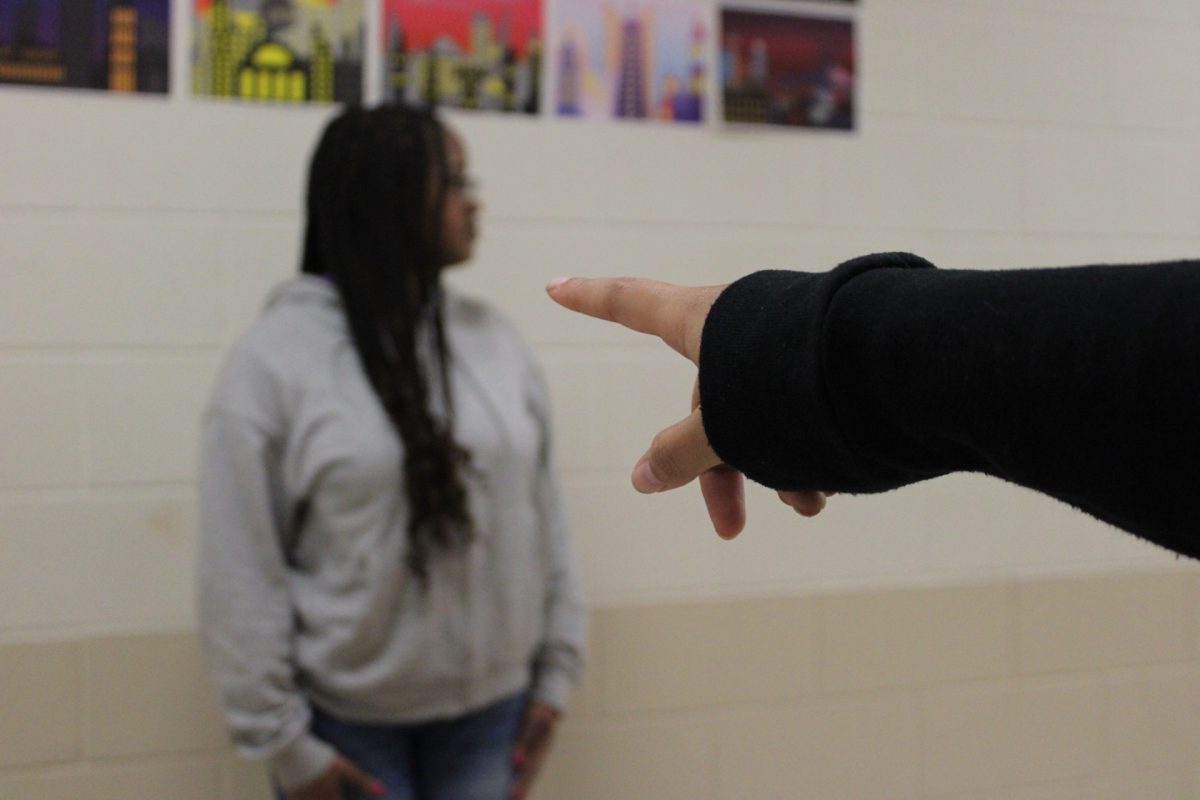 Judson alums, Kamara Manuel (against the wall) and Julie Rios (finger), help to demonstrate a depiction of racism.